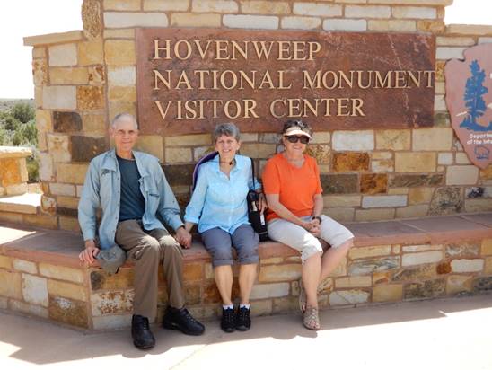 A group of people sitting on a bench in front of a building

Description automatically generated